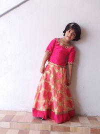 Portrait of smiling girl standing against wall