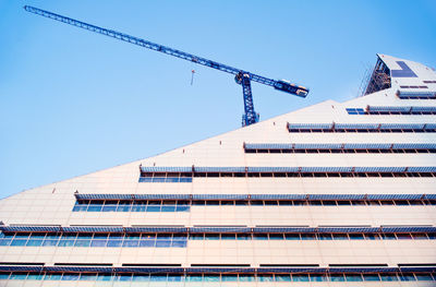 Low angle view of crane against clear blue sky