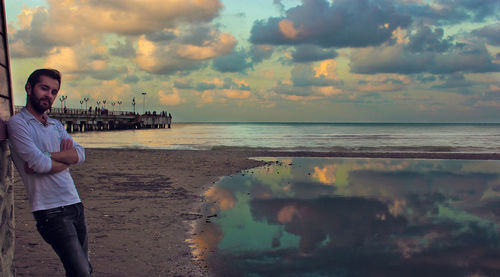 Man standing at beach against sky during sunset