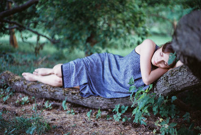 Woman sleeping on log in forest