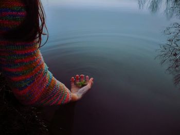 High angle view of woman holding leaf in lake