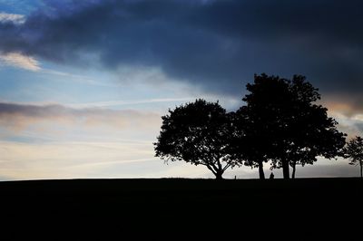 Silhouette of trees against cloudy sky