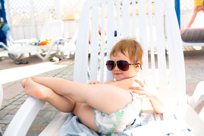 Small child in panama hat plays in the summer on sunny day near swimming pool