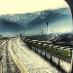 Road by railroad tracks against sky during winter