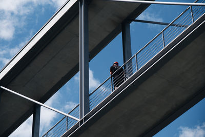 Low angle view of man standing on bridge against sky