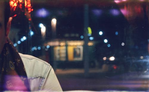 Rear view of person seen through glass window at night