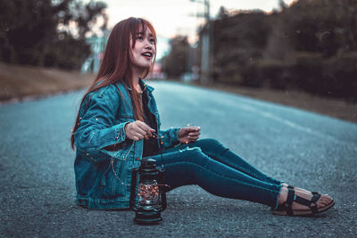 Young woman looking away while sitting outdoors