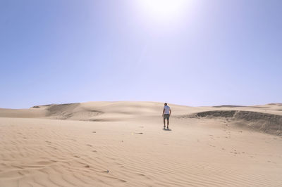 Rear view of woman standing on sand dune