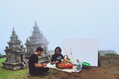 People sitting on temple against clear sky