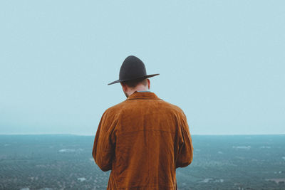 Rear view of man looking at sea against clear sky