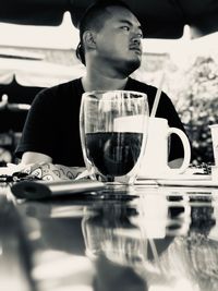 Reflection of man drinking glass on table at restaurant