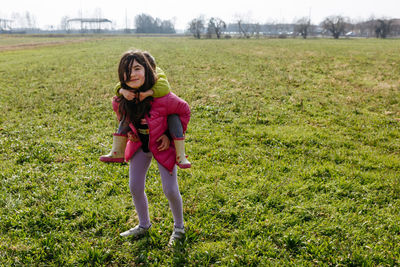 Elder girl watching camera with smaller child on her back doing piggyback ride