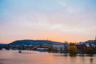 Dramatic sundown in the vltava river with a boat passing by and a gradient of orange to pink colors.