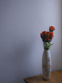 Flower vase on table against wall