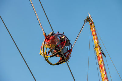 Low angle view of ferris wheel against clear blue sky