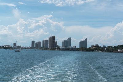 Sea by buildings in city against sky