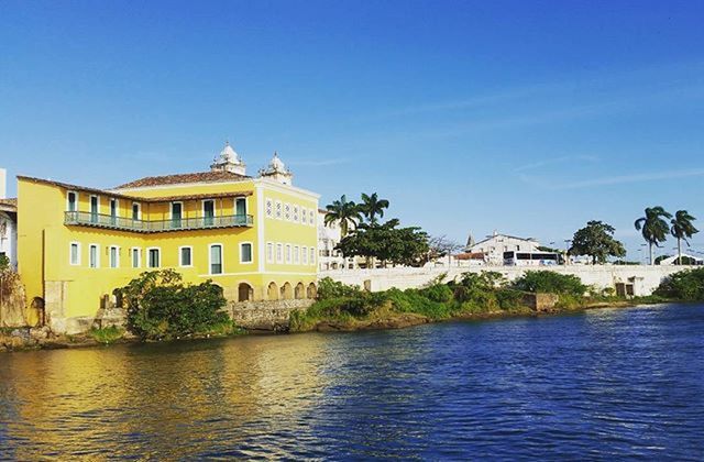 architecture, building exterior, built structure, water, waterfront, blue, clear sky, tree, house, residential building, sky, residential structure, copy space, day, reflection, rippled, sunlight, river, outdoors, building