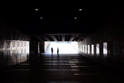 Silhouette people walking in illuminated tunnel