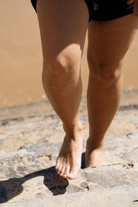 Low section of man standing on beach