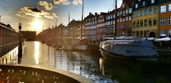 Boats moored in canal amidst city against sky