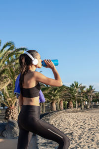 Beautiful fitness woman drinking water after training at the beach .vertical format.