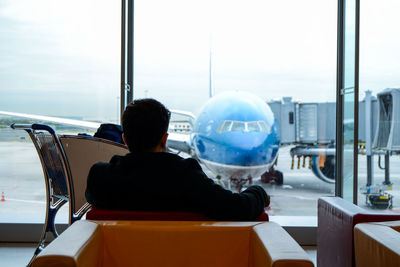 Rear view of man sitting at airport waiting area