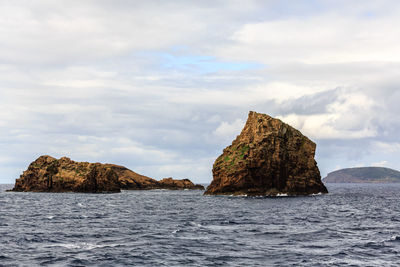 Rock formations in sea against sky