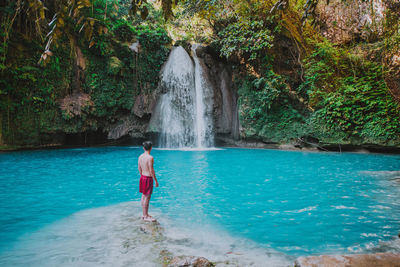 Man looking waterfall in forest