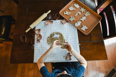 Overhead shot of child's making cookies with cookie cutters.