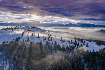 Scenic view of snow covered landscape against sky during sunset