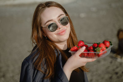 Portrait of young woman with strawberries