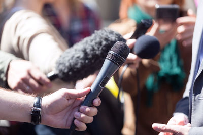 Cropped image of journalist holding microphones