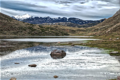 Scenic view of lake by snowcapped mountains against sky