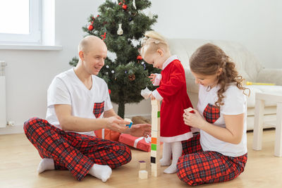 Happy family playing with christmas tree at home