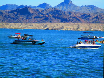 People on sea against mountains