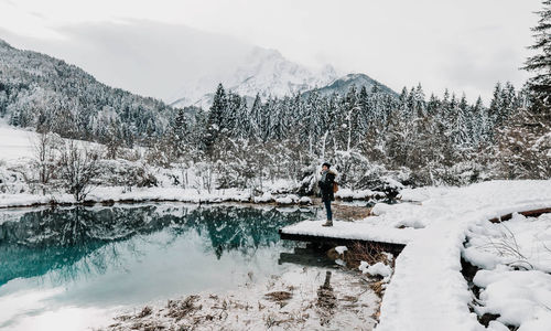 Woman standing on shore of lake in mountains. winter, snow, adventure.