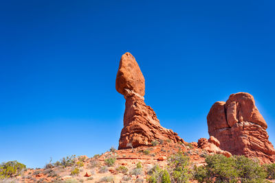 Low angle view of rock formation against clear blue sky