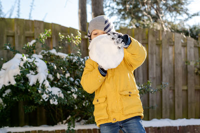 Little boy plays with snow in the backyard.