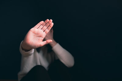 Cropped hand of woman gesturing against black background