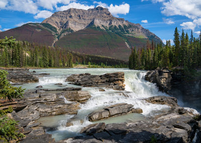 Scenic view of river flowing through mountains against sky