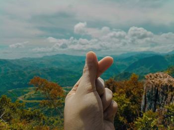 Cropped hand gesturing against landscape