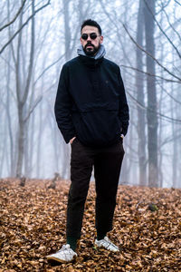 Full length of young man standing in forest during winter