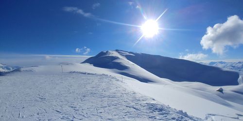 Scenic view of snowcapped mountains against blue sky