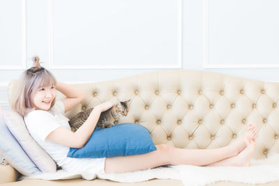Portrait of happy girl lying on sofa at home