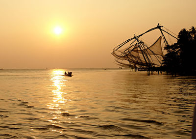 Silhouette of boat in sea at sunset