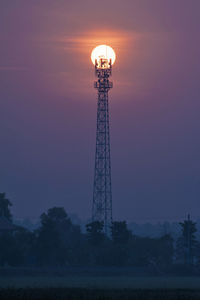 Low angle view of communications tower against sky at sunset