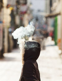 Digital composite image of smoke coming out from woman's hood