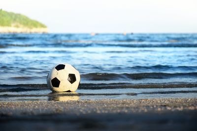 Soccer ball floating in the sea and hit the waves on the beach.