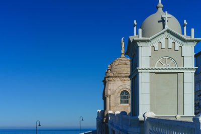 Low angle view of church by sea against clear blue sky