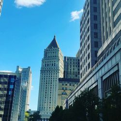 Low angle view of skyscrapers against blue sky